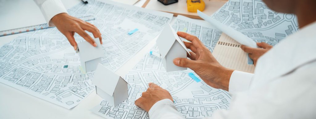אדריכל ומתכנן ערים בוחנים מפת תכנון עירונית ותוכניות בנייה על שולחן העבודה